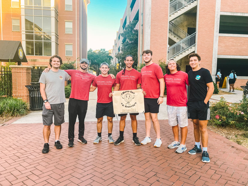 Group photo of fraternity students posing with a banner for fall 2023 move-in days.
